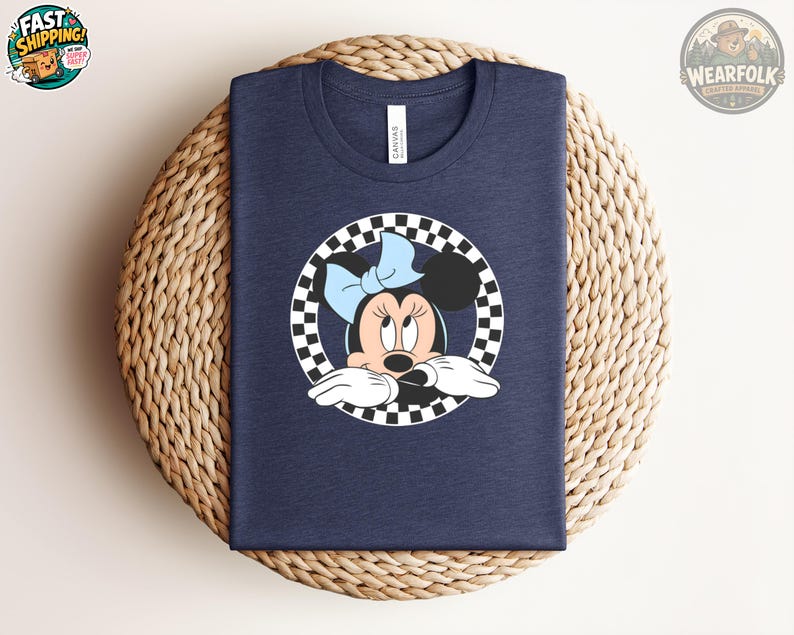 Navy Bella Canvas tee with Minnie Mouse character illustration in a checkered circle frame wearing a blue bow.
