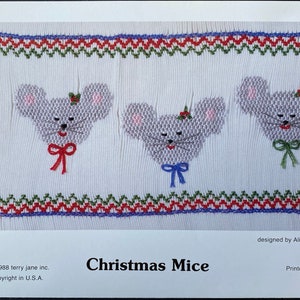 May include: A white fabric with three embroidered mice wearing red, blue, and green bows. The fabric has a green, red, and blue zig-zag border. The text "Christmas Mice" is printed below the fabric. The text "designed by Alicia Hamilton" is printed in the top right corner. The text "©1988 terry jane inc. Copyright in U.S.A." is printed in the bottom left corner. The text "Printed in U.S.A. #164" is printed in the bottom right corner.