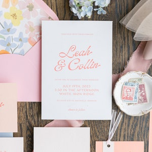 Peut inclure: Une suite d'invitation de mariage dans les tons rose et blanc. L'invitation présente les noms du couple, "Leah & Collin", en écriture cursive rose. La carte des détails présente le texte "the Details" en écriture cursive rose. La carte du menu présente le texte "Let's Eat" en écriture cursive rose.