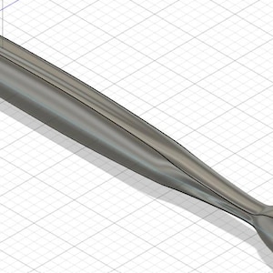 May include: A metallic gray, elongated object with a rounded tip and a bulbous end. The design features smooth, curved lines and a subtle, reflective surface. The object is set against a grid background.