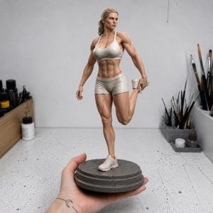 May include: A highly detailed, muscular female figurine standing on a circular gray base. The figure wears a light beige sports bra, matching shorts, and sneakers, captured in a dynamic stretching pose with one leg pulled back toward the glutes.