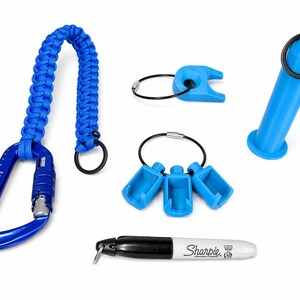 Puede incluir: Una colecci&oacute;n de accesorios azules, que incluyen un mosquet&oacute;n con un cord&oacute;n trenzado, varios llaveros y un marcador Sharpie azul. El mosquet&oacute;n tiene el texto "KN-1213-3". El Sharpie tiene el logotipo "Sharpie".