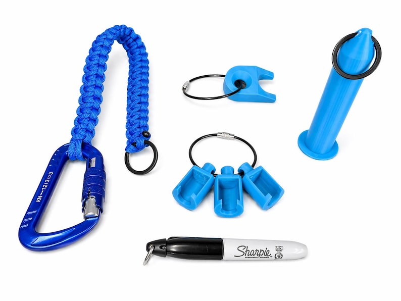 Puede incluir: Una colecci&oacute;n de accesorios azules, que incluyen un mosquet&oacute;n con un cord&oacute;n trenzado, varios llaveros y un marcador Sharpie azul. El mosquet&oacute;n tiene el texto "KN-1213-3". El Sharpie tiene el logotipo "Sharpie".