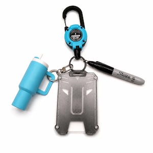 May include: A Drip Clip retractable carabiner in bright blue and black, attached to a translucent gray plastic ID badge holder, a miniature light blue tumbler keychain with a white straw, and a gray Sharpie Fine Point permanent marker.