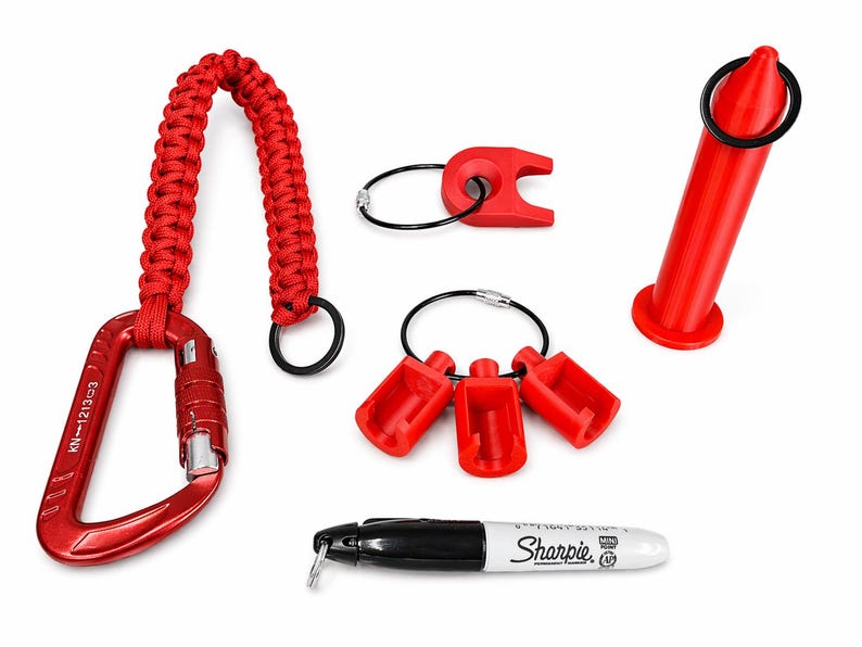Puede incluir: Una colecci&oacute;n de accesorios rojos, que incluye un mosquet&oacute;n con asa trenzada, llaveros con componentes de pl&aacute;stico rojo y un objeto cil&iacute;ndrico rojo. Tambi&eacute;n se incluye un rotulador Sharpie en blanco y negro.