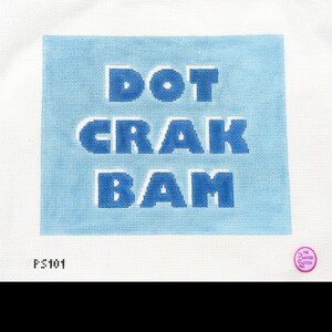 May include: A needlepoint canvas with the words "DOT CRAK BAM" in blue block letters on a light blue square. The canvas is on a white background. The text "FS101" is at the bottom left.