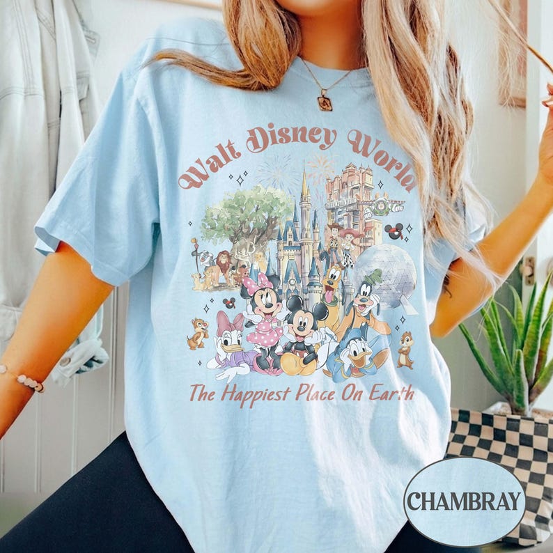 May include: Light blue t-shirt with a graphic of Disney characters and the text "Walt Disney World" and "The Happiest Place On Earth". The graphic includes Mickey Mouse, Minnie Mouse, Donald Duck, and other characters.