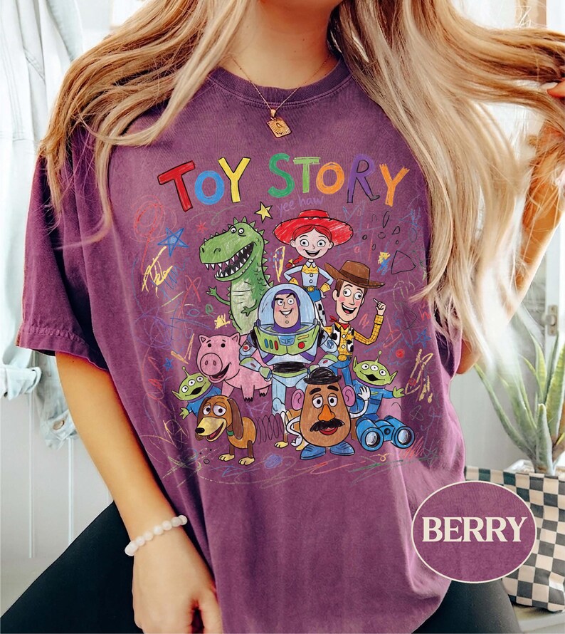 Pode incluir: Camiseta cor de berry com a inscri&ccedil;&atilde;o "TOY STORY" sobre um gr&aacute;fico colorido de personagens do filme de anima&ccedil;&atilde;o. O design inclui Woody, Buzz Lightyear e outros personagens amados. A camisa tem um visual vintage.
