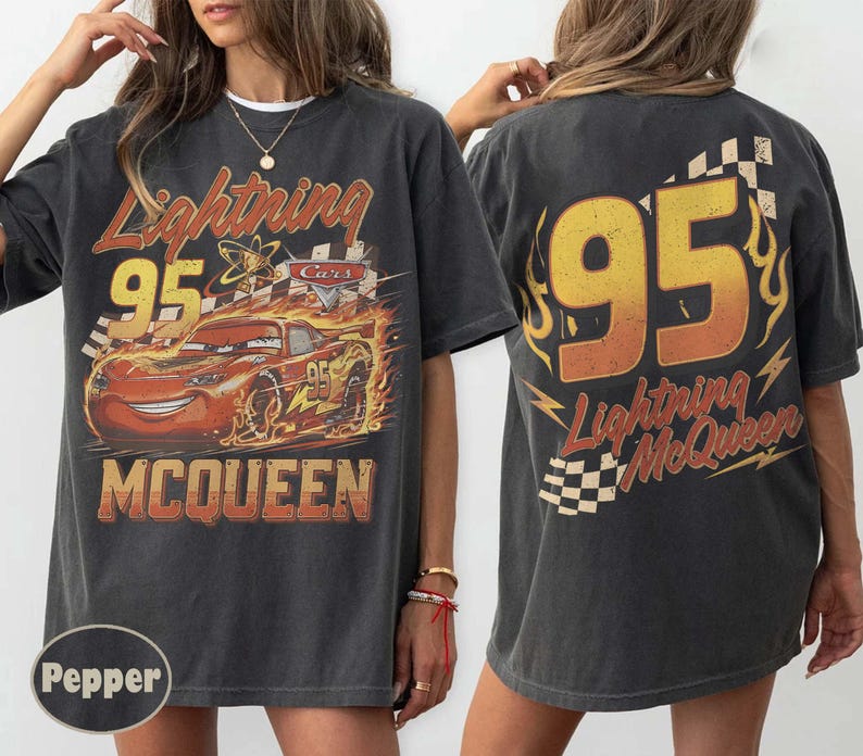 Puede incluir: Camiseta gris oscuro con un dise&ntilde;o de Rayo McQueen de la pel&iacute;cula Cars. El dise&ntilde;o frontal incluye el n&uacute;mero 95, el nombre del personaje y llamas. La parte trasera de la camiseta tambi&eacute;n muestra el n&uacute;mero 95 y el nombre de Rayo McQueen.