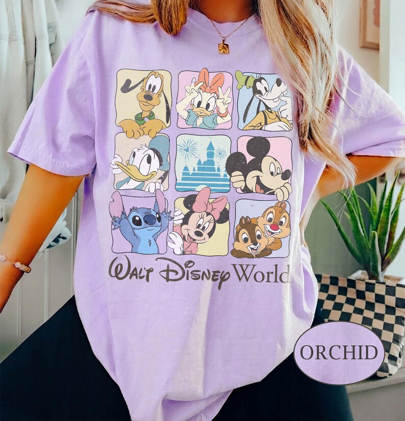 May include: Orchid-colored t-shirt featuring a grid of Disney characters including Mickey Mouse, Donald Duck, and Stitch. The words "Walt Disney World" are printed below the grid. The shirt has short sleeves.