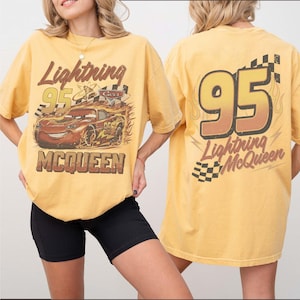 Puede incluir: Camiseta amarillo mostaza con Lightning McQueen de la pel&iacute;cula Cars. El gr&aacute;fico frontal muestra a McQueen con llamas y el texto "Lightning 95 McQueen". La parte trasera muestra "95" con llamas y "Lightning McQueen".