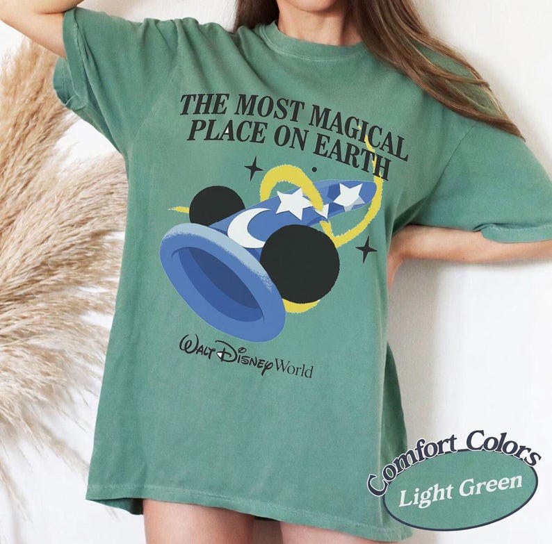 Puede incluir: Camiseta verde claro con el texto "THE MOST MAGICAL PLACE ON EARTH" y un gr&aacute;fico del sombrero y las orejas de Mickey Mouse. La camiseta tambi&eacute;n tiene las palabras "Walt Disney World" impresas. La esquina inferior derecha de la camiseta dice "Comfort Colors Light Green".
