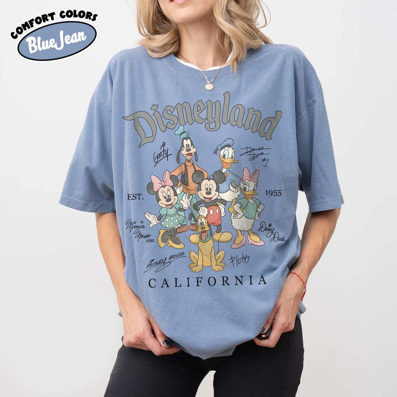 May include: Blue short-sleeved t-shirt with a Disneyland graphic. The graphic features Mickey Mouse, Minnie Mouse, Donald Duck, Goofy, Pluto, and Daisy Duck. The text "Disneyland California" is printed below the characters.
