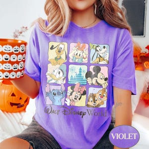 May include: A violet t-shirt featuring a grid of Disney characters including Mickey Mouse, Donald Duck, and Stitch. The shirt has the text "Walt Disney World" printed below the grid. A pumpkin-shaped container is held in the left hand.