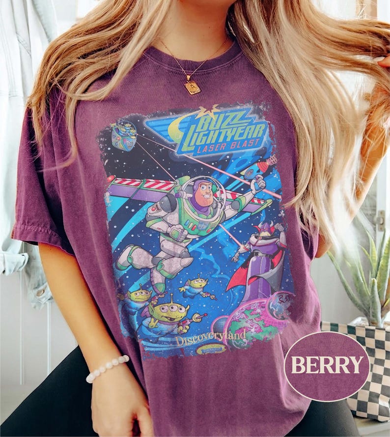 Puede incluir: Camiseta de color bayas con un gr&aacute;fico de Buzz Lightyear de la pel&iacute;cula Toy Story. El dise&ntilde;o incluye las palabras "Buzz Lightyear Laser Blast" y "Discoveryland" con im&aacute;genes de los personajes en una escena espacial.