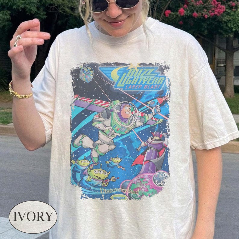 Puede incluir: Camiseta de color marfil con un gr&aacute;fico colorido de Buzz Lightyear de la pel&iacute;cula "Lightyear". El dise&ntilde;o incluye el texto "Buzz Lightyear Laser Blast" e im&aacute;genes de extraterrestres y Zurg. La camiseta tiene un aspecto vintage.