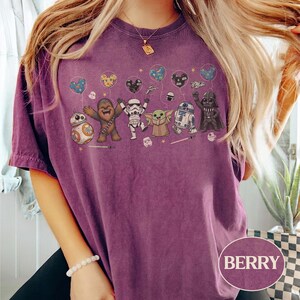 May include: Berry-colored t-shirt featuring a Star Wars character design. The graphic includes BB-8, Chewbacca, a Stormtrooper, Grogu, R2-D2, and Darth Vader, each holding a balloon. The word "BERRY" is printed on the bottom right.