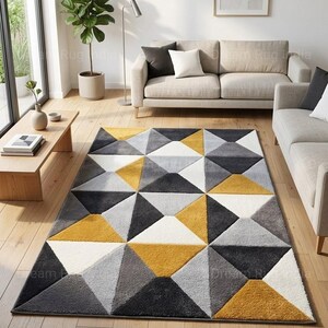 May include: A geometric patterned rug with a modern design. The rug features a repeating pattern of triangles in shades of grey, white, and yellow. The rug is placed on a wooden floor in a living room setting.