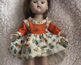 Vintage Vogue GINNY-pop uit de jaren 50, bruin haar, blauwe ogen, oranje bloemenjurk met bloemen