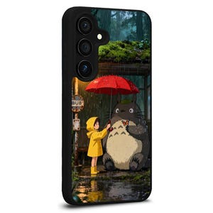 May include: Black phone case featuring a scene from the animated film, My Neighbor Totoro. The image shows a girl in a yellow raincoat and Totoro under a red umbrella at a bus stop in the rain.