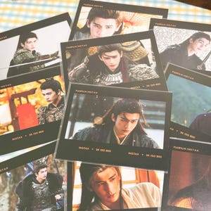 May include: A collection of Fujifilm Instax prints featuring a person with long dark hair in various historical costumes. Each print includes the text Fujifilm Instax, Instax, and 36 ISO 800. The images show the person in armor, robes, and outdoor settings.