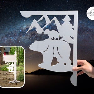 Puede incluir: Puesto de buzón de madera blanco con un diseño recortado de un oso y un cachorro frente a una cordillera. El poste está montado sobre una base de madera y tiene una bandera roja en la parte superior. El diseño está creado por Stagwood.