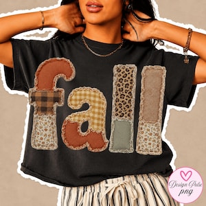Op de afbeelding: Een zwart t-shirt met het woord fall in grote, getextureerde letters in patchworkstijl. Elke letter is samengesteld uit verschillende stofpatronen, waaronder bruin, ruitjes, bloemen, luipaardprint en effen beige, met gerafelde randen.