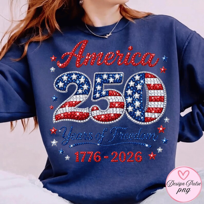 Puede incluir: Sudadera azul marino con el texto "America 250 Years of Freedom 1776-2026" en pedrer&iacute;a roja, blanca y azul. El n&uacute;mero "250" est&aacute; dise&ntilde;ado con estrellas y rayas.
