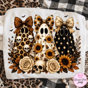 May include: A white t-shirt featuring a graphic of three ghosts wearing large bows. The first ghost has a leopard print with skulls, the second has a sunflower pattern, and the third is black with gold polka dots. Includes roses and a skull.