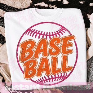 以下が含まれることがあります： ピンク色の野球の輪郭の中に、オレンジ色の「BASE BALL」の文字がかすれたデザインの白いクルーネックのスウェットシャツ。 ヴィンテージ感のあるデザインで、スポーツファンに最適です。