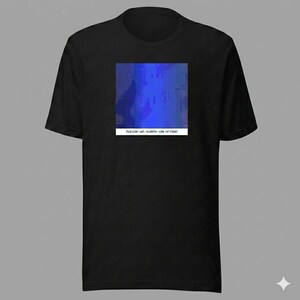 Könnte beinhalten: Schwarzes T-Shirt mit einem quadratischen, abstrakten blauen Design. Das Design zeigt eine Mischung aus hellen und dunklen Blautönen, mit einem rechteckigen weißen Balken am unteren Rand mit Text. Ein lässiges T-Shirt.