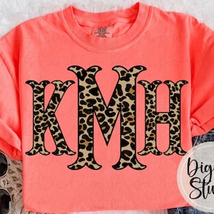 May include: Coral-colored sweatshirt with the letters "KMH" in a leopard print design. The letters are large and centered on the shirt. The text "DigiBo Studio" is in the lower right corner.