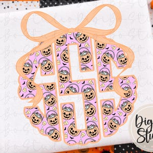 May include: A circular monogram design featuring a light peach-colored bow at the top. The letters are filled with a repeating pattern of orange jack-o'-lantern candy buckets, yellow and white candy corn, and small black bats on a light pink background.