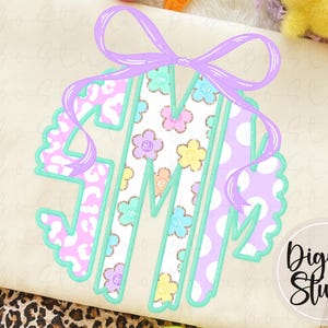 May include: A monogram design with the letters G, M, and J, a scalloped edge, and a bow. The letters have a floral and polka dot pattern in pastel colours, with a light green outline. The design is on a cream-coloured background.