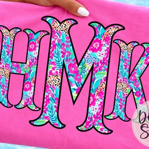 Puede incluir: Una tela rosa brillante doblada muestra las letras HMK en un patrón floral con contornos negros. El diseño floral incluye flores rosas, hojas turquesas y detalles de estampado de leopardo. El logotipo de DigiBo Studio está en la esquina inferior derecha.