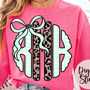 May include: Pink crew neck sweatshirt with a monogram design featuring the letters RMH. The monogram includes a bow, leopard print, and a light green gingham pattern. The DigiBo Studio logo is in the lower right corner.