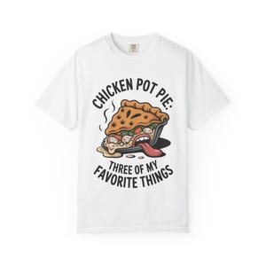 May include: White t-shirt with a graphic of a chicken pot pie with a long tongue sticking out. The text on the shirt reads "Chicken Pot Pie: Three of My Favorite Things."