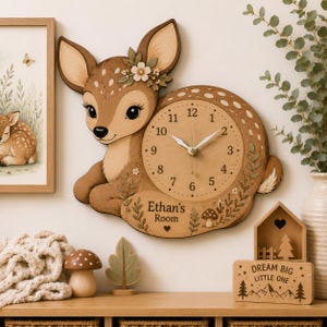 Könnte beinhalten: Eine Wanduhr aus Holz in Form eines Rehkitzes mit großen Augen, floralen Akzenten und einem runden Zifferblatt mit schwarzen Zahlen und weißen Zeigern. Der untere Teil zeigt den Text Ethan's Room, ein Herz und einen Pilz.
