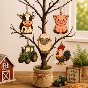 May include: Five wooden hanging ornaments featuring a black and white cow with a bell, a pink pig, a fluffy white sheep, a green tractor, and a colorful rooster. Each ornament is suspended by a jute twine loop from a decorative tabletop tree.