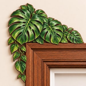May include: A decorative corner accent piece featuring a cluster of green monstera leaves and trailing foliage. The botanical design is rendered in shades of deep and light green, designed to be mounted on the upper corner of a wooden door frame.