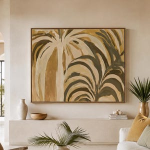 May include: A large rectangular wall art piece featuring an abstract painting of palm leaves in shades of mustard yellow, olive green, and cream, enclosed in a thin wooden frame and displayed above a long, low, light-coloured stone console table.