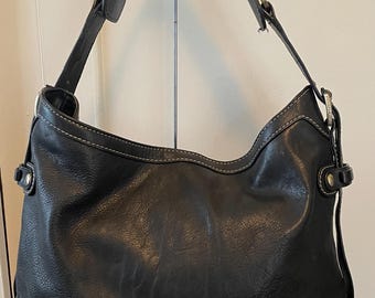 May include: Black leather shoulder bag with a gold Michael Kors logo and white stitching.