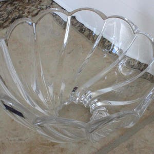 May include: A clear glass bowl with a scalloped edge and a wavy design. The bowl is empty and appears to be made of crystal.