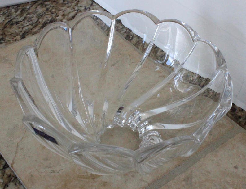 May include: A clear glass bowl with a scalloped edge and a wavy design. The bowl is empty and appears to be made of crystal.
