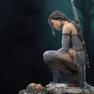 Puede incluir: Escultura detallada de una mujer con un vestido azul claro y fluido, arrodillada con la cabeza inclinada. Una espada está atada a su espalda. Una cabeza esculpida descansa en el agua frente a ella. La estatua tiene una expresión serena y contemplativa.