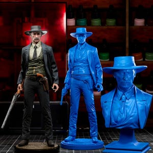 Puede incluir: Tres figuras de vaqueros se exhiben contra un fondo de botes de pintura. La primera es una figura detallada y completamente pintada con traje y sombrero negros, sosteniendo un rifle. La segunda es una figura azul sólida, y la tercera es un busto azul.