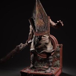 May include: A detailed figurine of a character with a pyramid-shaped head, holding a large blade. The figure is clad in a leather-like apron and stands on a detailed, blood-splattered base. The color palette is primarily brown and red.