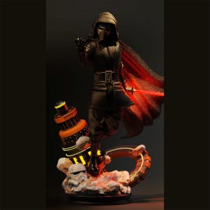 May include: A detailed figurine of a character in a black suit with a red cape, holding a red lightsaber. The figure is standing on a base with a Stormtrooper helmet and a futuristic orange and yellow structure. The background is dark.