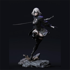 Może przedstawiać: Szczegółowa figurka postaci w czarnej sukience z białymi akcentami, czarnymi rękawiczkami i kozakami do ud. Postać ma krótkie białe włosy i opaskę na oczy. Trzyma miecz i stoi na skalistej podstawie.