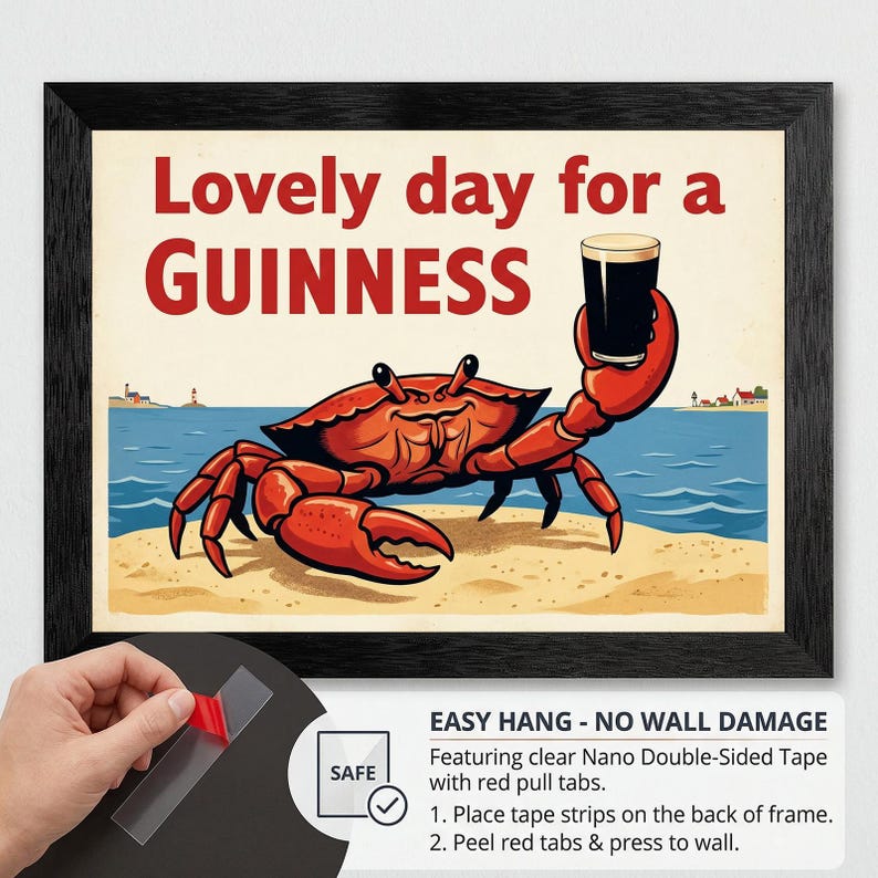 May include: Framed art print featuring a cartoon crab holding a pint of Guinness. The text "Lovely day for a Guinness" is displayed above the crab. The artwork is set on a beach with a blue ocean and a lighthouse in the background.